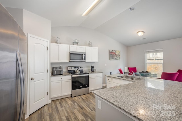 1125 Silvertrace Dr, Salisbury, NC 28144 - kitchen featuring lofted ceiling, light wood-style floors, white cabinetry, a sink, and stainless steel appliances