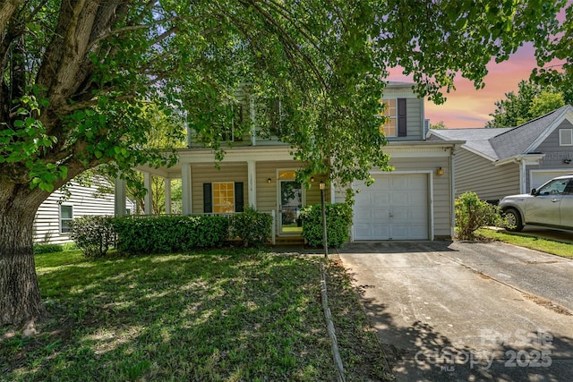 obstructed view of property featuring a porch, an attached garage, driveway, and a front yard