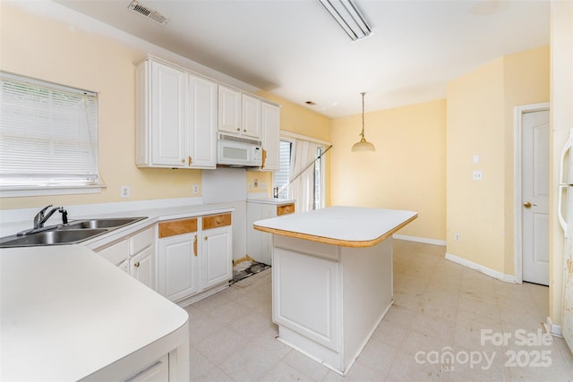 kitchen featuring light floors, visible vents, white microwave, and a sink