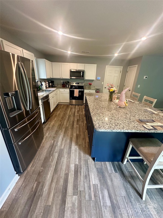 1070 Glenbriar Ct, Woodleaf, NC 27054 - kitchen with light stone countertops, stainless steel appliances, a kitchen bar, dark wood-type flooring, and white cabinetry