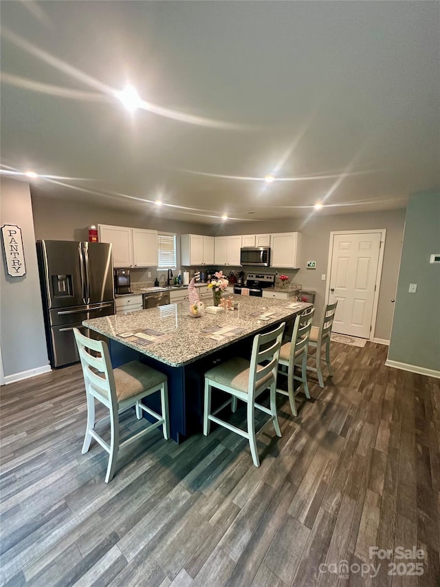 1070 Glenbriar Ct, Woodleaf, NC 27054 - kitchen with white cabinets, stainless steel appliances, dark wood-style flooring, a large island, and light stone countertops