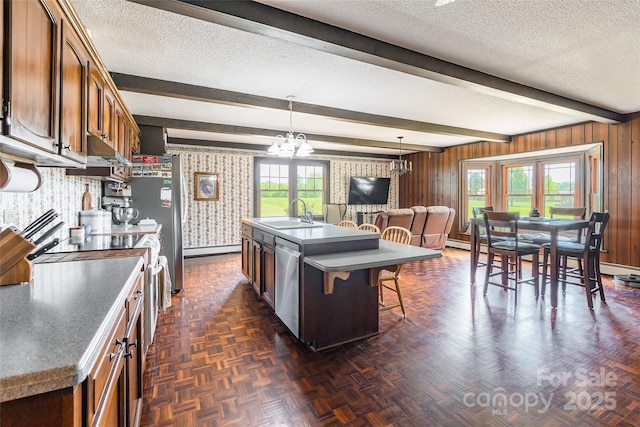 kitchen featuring a kitchen breakfast bar, a textured ceiling, a sink, a notable chandelier, and appliances with stainless steel finishes