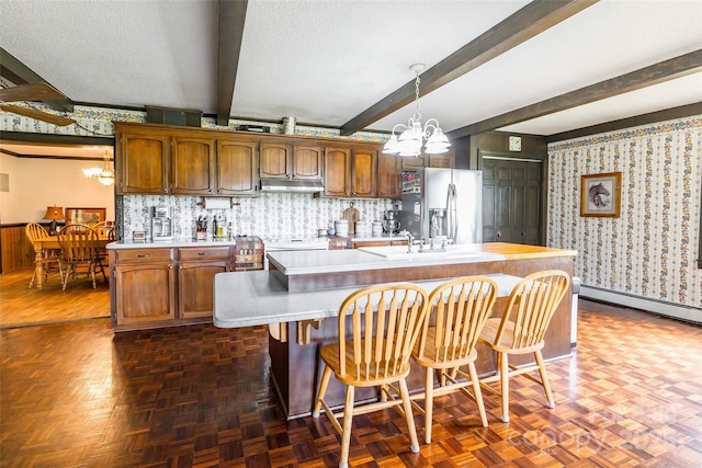 kitchen with a chandelier, light countertops, stainless steel refrigerator with ice dispenser, and beamed ceiling
