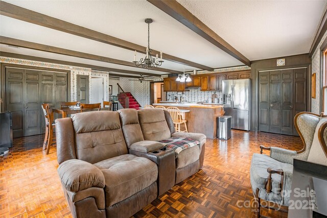 living room featuring a chandelier, beam ceiling, and stairs