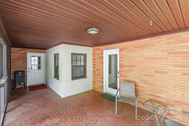 property entrance with brick siding and a patio