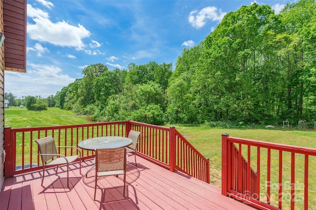wooden deck with a lawn and outdoor dining area