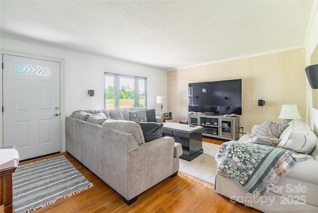 living room with wallpapered walls, wood finished floors, a textured ceiling, and crown molding
