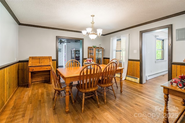 dining area featuring a baseboard radiator, a wainscoted wall, a textured ceiling, and ornamental molding