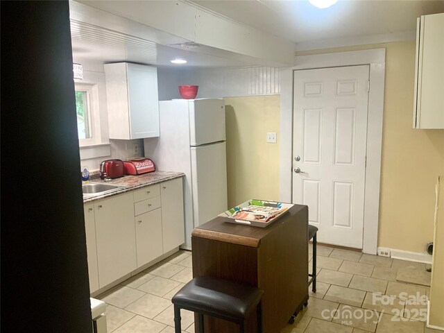 439 17th St, Cramerton, NC 28032 - kitchen with freestanding refrigerator, light tile patterned floors, white cabinets, and a sink