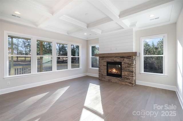 unfurnished living room with wood finished floors, beam ceiling, a stone fireplace, and coffered ceiling