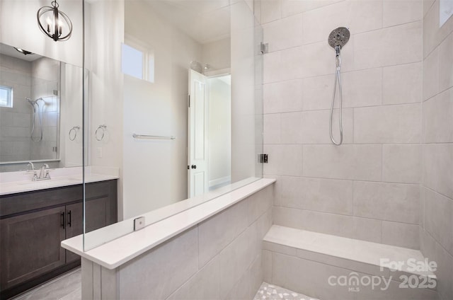 full bathroom with tiled shower, vanity, and plenty of natural light