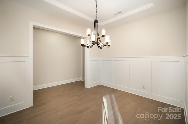unfurnished dining area featuring an inviting chandelier, ornamental molding, and a decorative wall