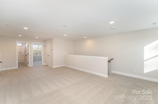 empty room with baseboards, light carpet, visible vents, and recessed lighting