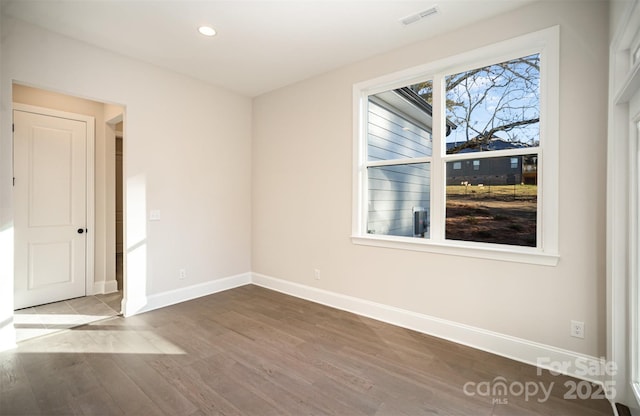 spare room with wood finished floors, recessed lighting, visible vents, and baseboards