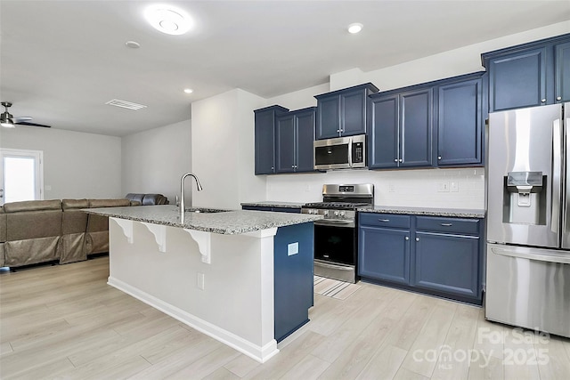 147 Morning Gap Pkwy, Fort Mill, SC 29715 - kitchen featuring a kitchen breakfast bar, a sink, light wood-style floors, blue cabinetry, and appliances with stainless steel finishes