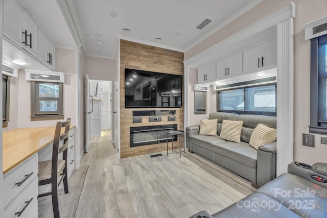 living room featuring crown molding, light wood-style flooring, and a fireplace