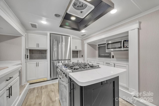 kitchen with stainless steel appliances, white cabinetry, a center island, light wood-type flooring, and light stone countertops