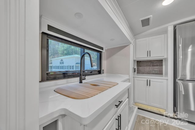 kitchen featuring freestanding refrigerator, white cabinets, and light stone counters