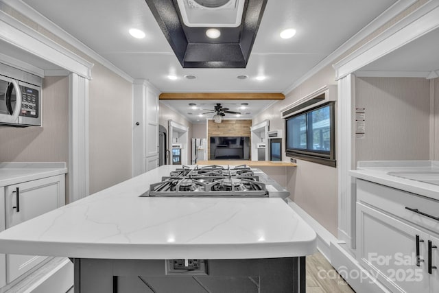 kitchen with a center island, gas stovetop, white cabinetry, ornamental molding, and light wood-style flooring