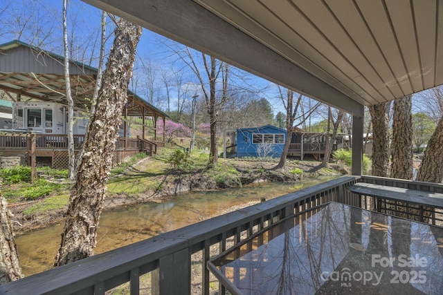 wooden terrace with an outdoor structure and a water view
