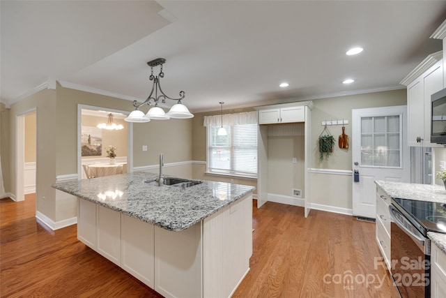 kitchen with stainless steel appliances, a sink, white cabinetry, light stone counters, and ornamental molding