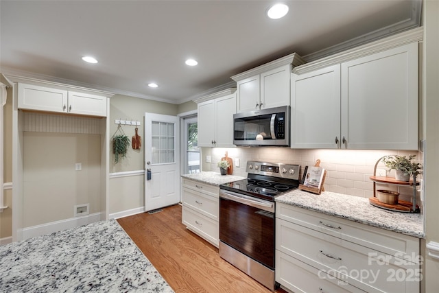 kitchen with stainless steel appliances, light wood-style flooring, backsplash, white cabinetry, and crown molding