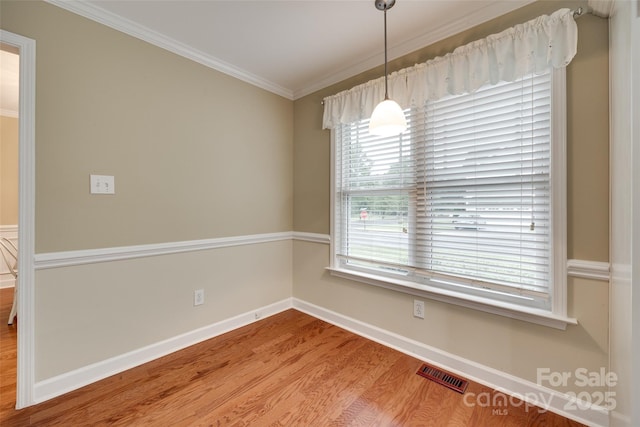 unfurnished dining area with baseboards, crown molding, wood finished floors, and visible vents
