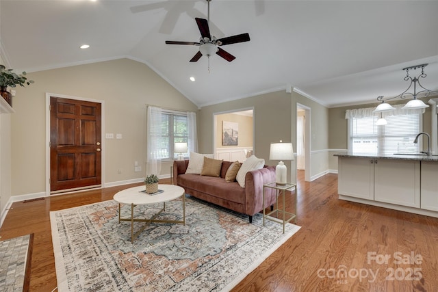 living room featuring lofted ceiling, plenty of natural light, a ceiling fan, and light wood-style flooring