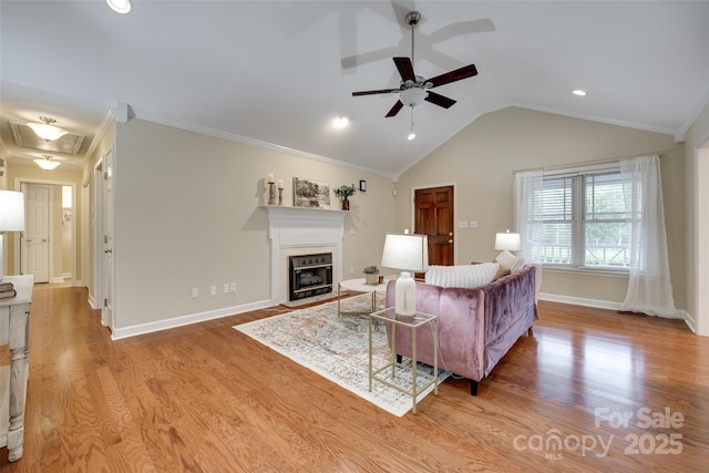 living area featuring a ceiling fan, a glass covered fireplace, light wood-style flooring, baseboards, and lofted ceiling