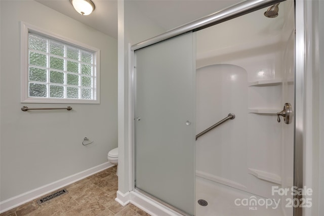bathroom featuring baseboards, toilet, visible vents, and a stall shower