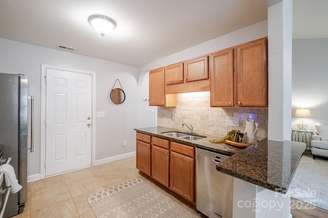 kitchen featuring stainless steel appliances, a sink, dark stone countertops, visible vents, and decorative backsplash