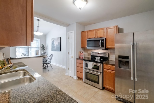 kitchen with lofted ceiling, stainless steel appliances, a sink, baseboards, and decorative backsplash