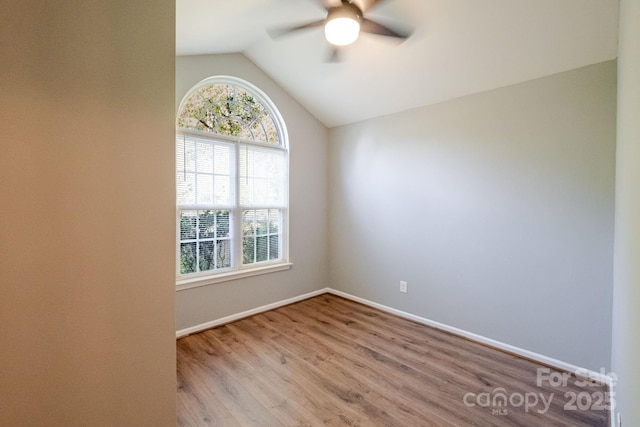 unfurnished room featuring vaulted ceiling, plenty of natural light, wood finished floors, and ceiling fan