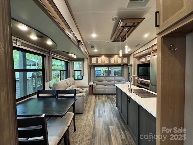 kitchen featuring open floor plan, a sink, dark wood finished floors, light countertops, and stainless steel fridge