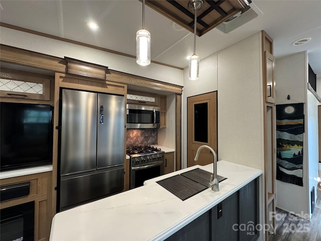 kitchen featuring appliances with stainless steel finishes, a sink, backsplash, decorative light fixtures, and wood finished floors