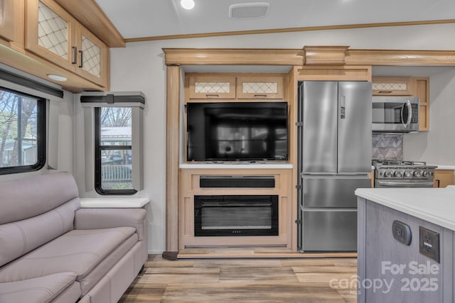kitchen with stainless steel appliances, light wood-style floors, open floor plan, light countertops, and crown molding