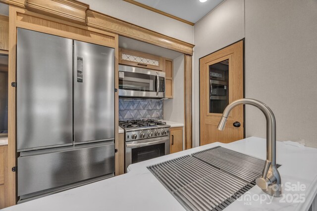 kitchen featuring stainless steel appliances, backsplash, a sink, and light countertops
