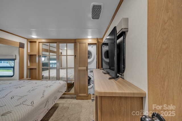 bedroom with stacked washer / dryer and light carpet