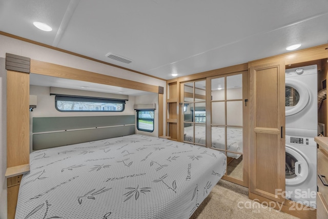 bedroom with estacked washer and dryer, light colored carpet, and recessed lighting