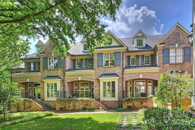 back of house featuring a shingled roof, a yard, stairs, and brick siding