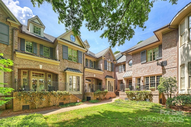 rear view of house featuring brick siding and a yard