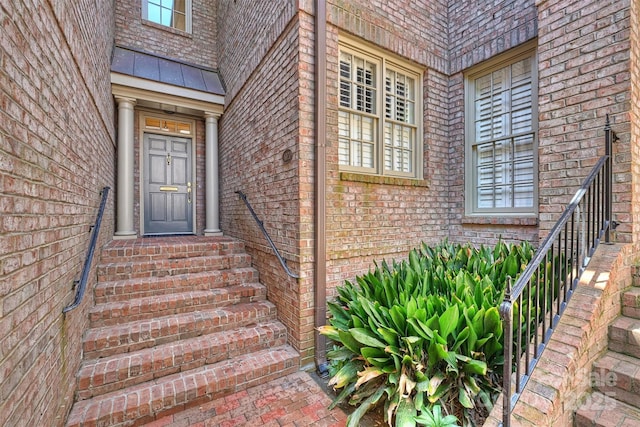 doorway to property with brick siding, a standing seam roof, and metal roof