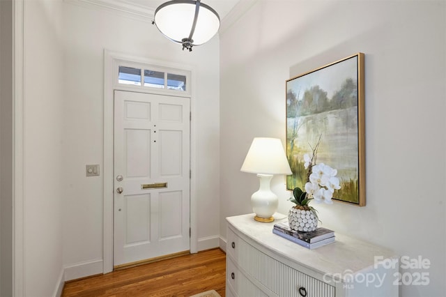 foyer with baseboards, light wood-style floors, and ornamental molding
