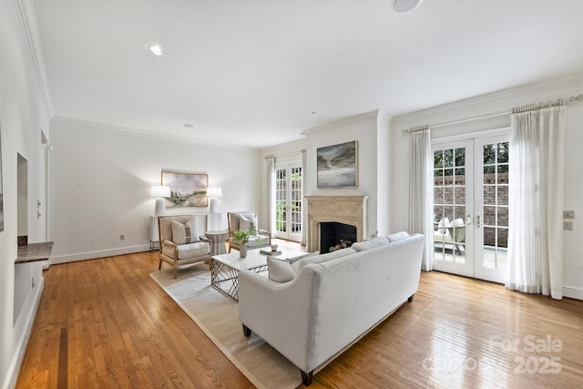 living room with french doors, a fireplace, light wood-style flooring, and crown molding