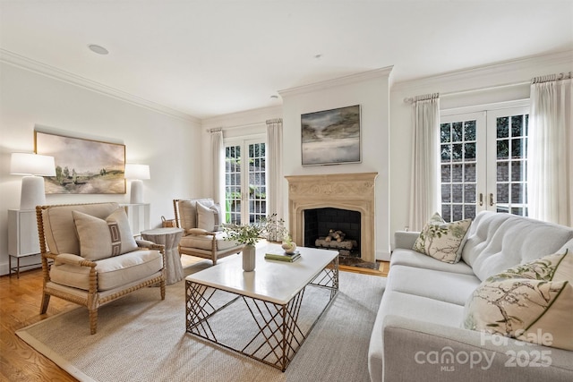 living area with crown molding, french doors, wood finished floors, and a fireplace
