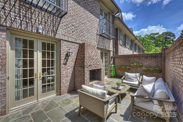 view of patio featuring a fenced backyard, an outdoor living space with a fireplace, and french doors