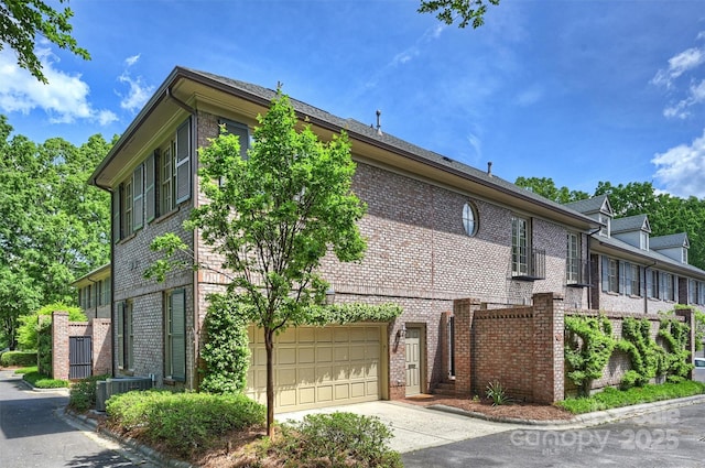 view of home's exterior featuring brick siding, driveway, central AC unit, and a garage