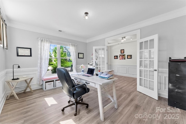 office space featuring french doors, a decorative wall, crown molding, light wood finished floors, and a wainscoted wall