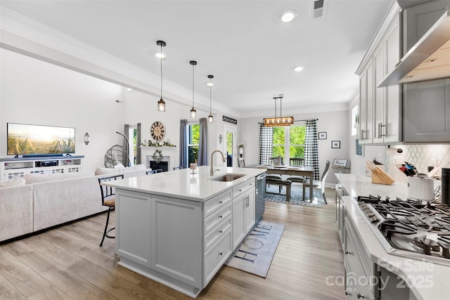 kitchen featuring a sink, stainless steel appliances, light countertops, light wood-style flooring, and ornamental molding