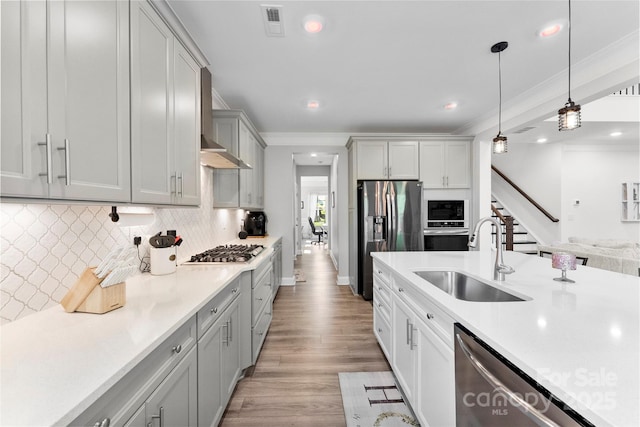 kitchen featuring a sink, stainless steel appliances, light countertops, decorative backsplash, and hanging light fixtures
